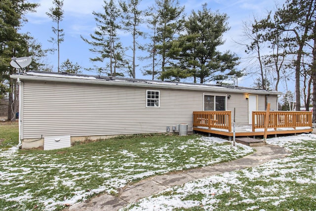 snow covered rear of property featuring a lawn and a deck