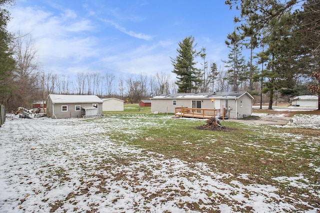 snow covered property featuring an outdoor structure, a yard, and a wooden deck