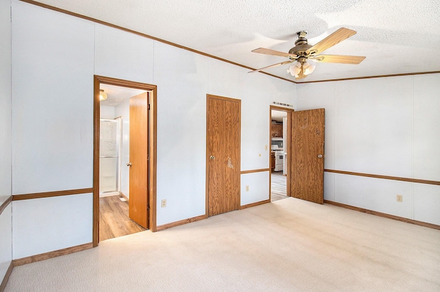 unfurnished bedroom featuring a textured ceiling, light colored carpet, ceiling fan, crown molding, and connected bathroom