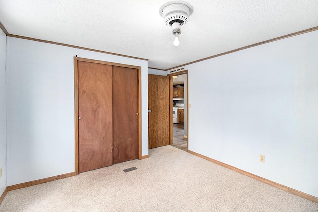 unfurnished bedroom featuring a textured ceiling, ornamental molding, light carpet, and a closet