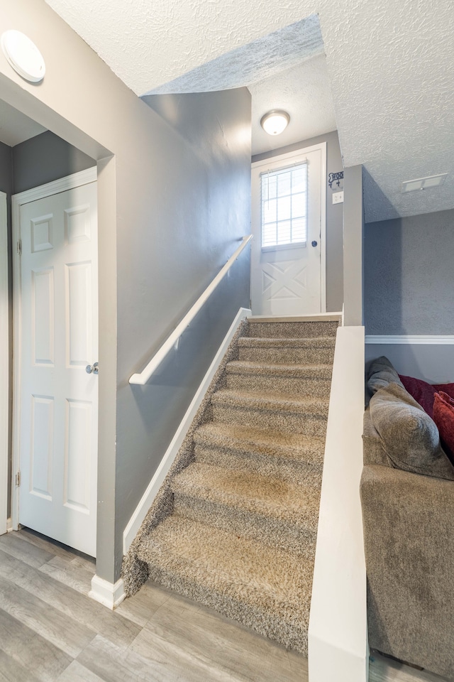 stairs with hardwood / wood-style flooring and a textured ceiling