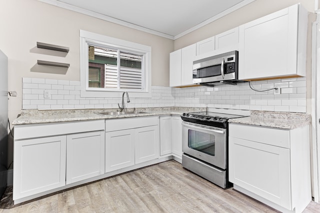 kitchen featuring appliances with stainless steel finishes, light hardwood / wood-style floors, white cabinetry, and sink