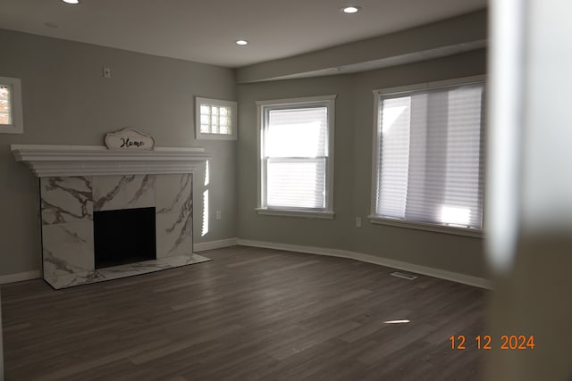 unfurnished living room featuring a high end fireplace and dark hardwood / wood-style floors