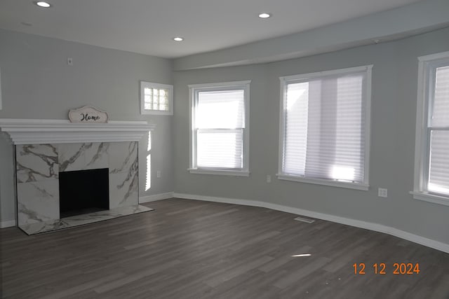 unfurnished living room featuring dark wood-type flooring and a premium fireplace