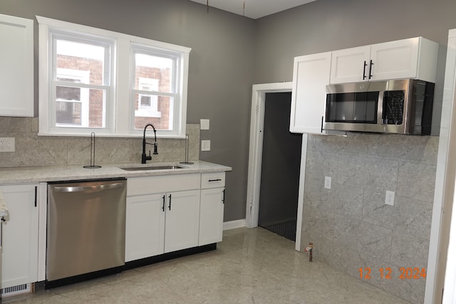 kitchen featuring light stone counters, sink, white cabinetry, and stainless steel appliances