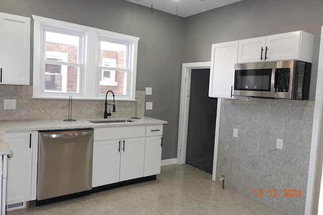 kitchen with appliances with stainless steel finishes, light stone counters, ceiling fan, sink, and white cabinets