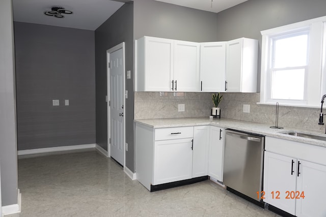 kitchen featuring light stone counters, white cabinetry, stainless steel dishwasher, and sink