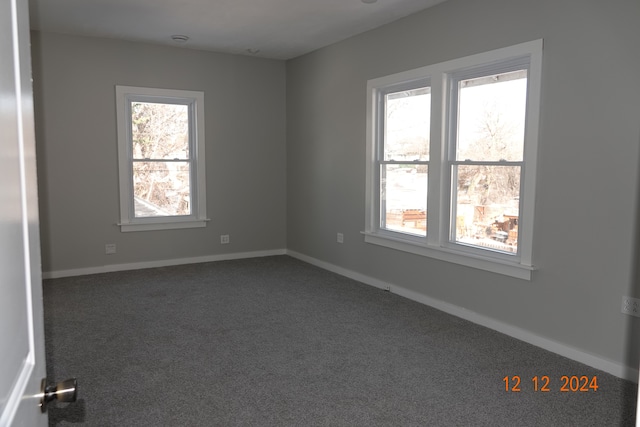 unfurnished room featuring dark colored carpet