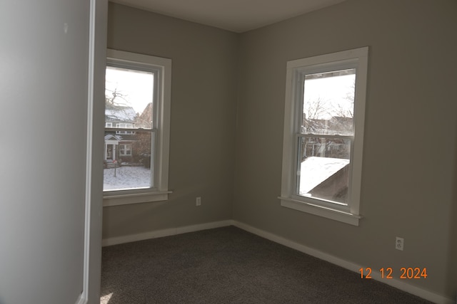 empty room with dark carpet and a healthy amount of sunlight