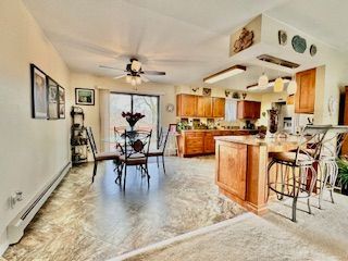 kitchen with a breakfast bar area, kitchen peninsula, ceiling fan, and baseboard heating