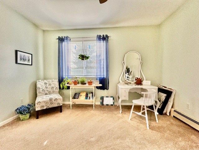 living area featuring ceiling fan, carpet floors, and baseboard heating