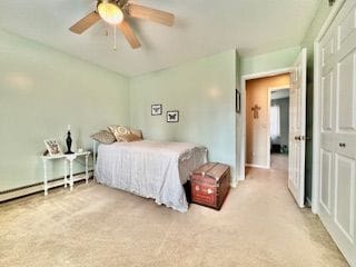 bedroom featuring carpet, ceiling fan, baseboard heating, and a closet