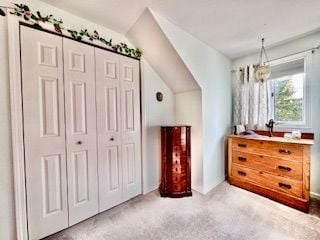 carpeted bedroom featuring a closet and lofted ceiling