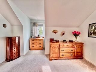 bedroom with light carpet and vaulted ceiling