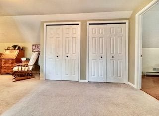 bedroom with carpet flooring, lofted ceiling, and multiple closets