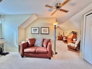 sitting room with light carpet, ceiling fan, and vaulted ceiling