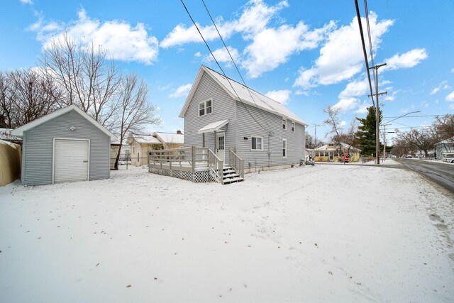 snow covered property featuring a deck and an outbuilding