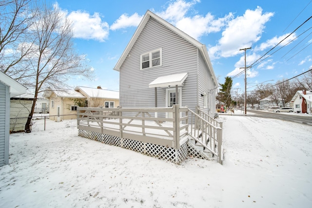 snow covered rear of property with a deck