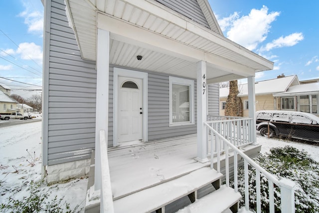 snow covered property entrance featuring covered porch