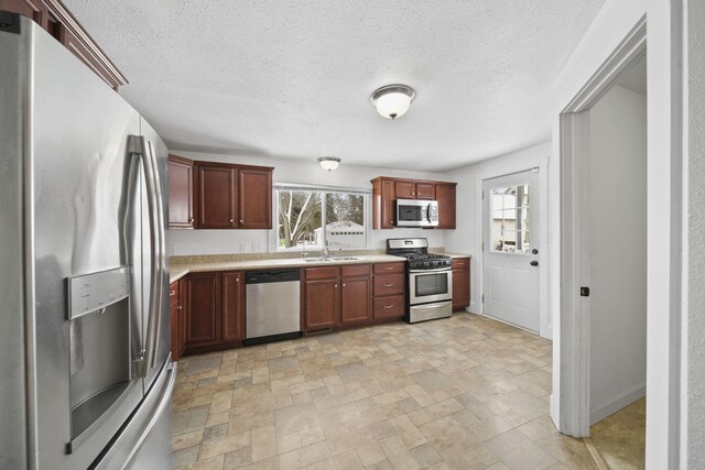 kitchen with appliances with stainless steel finishes, a textured ceiling, and sink