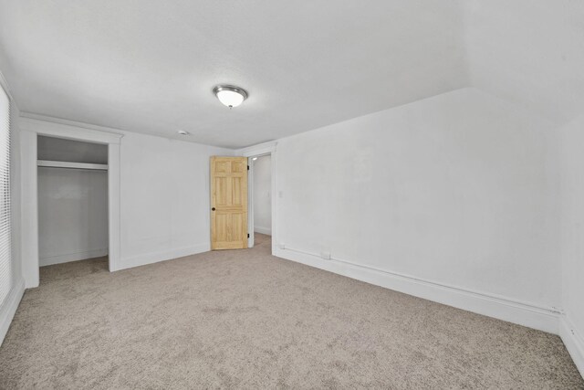 unfurnished bedroom featuring a closet, vaulted ceiling, and carpet