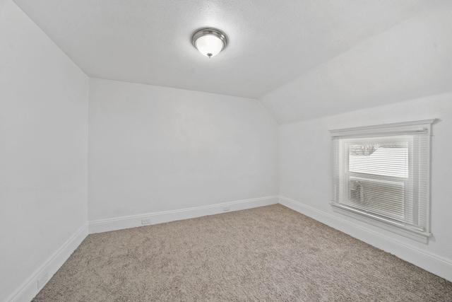 additional living space featuring carpet flooring, a textured ceiling, and vaulted ceiling