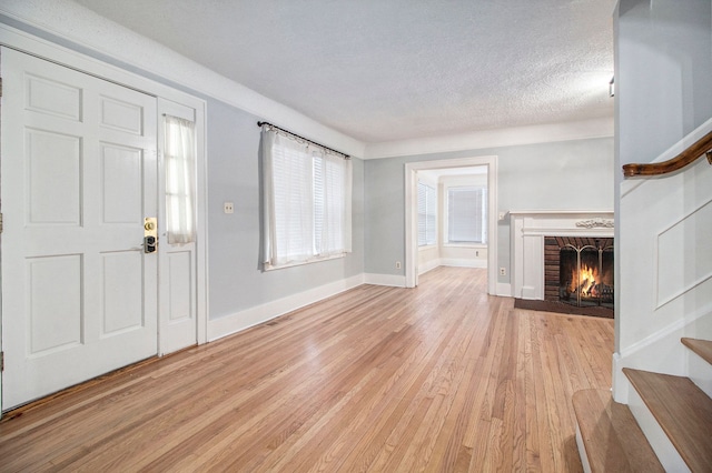 foyer featuring light hardwood / wood-style floors, a textured ceiling, and a brick fireplace