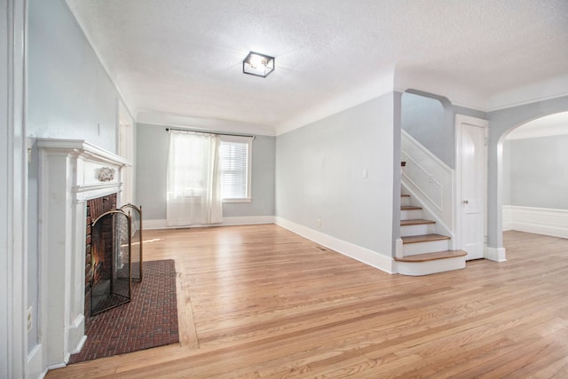 unfurnished living room with a fireplace, light hardwood / wood-style floors, and a textured ceiling