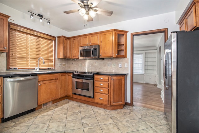 kitchen featuring ceiling fan, sink, light hardwood / wood-style flooring, decorative backsplash, and appliances with stainless steel finishes