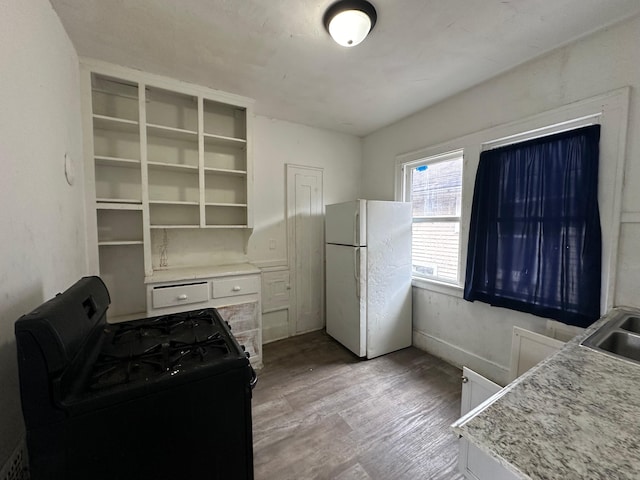 kitchen featuring sink, white refrigerator, black range with gas cooktop, white cabinets, and light wood-type flooring