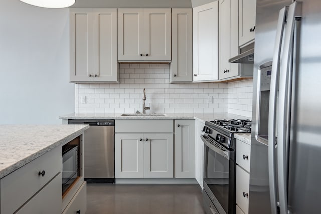 kitchen featuring light stone countertops, backsplash, stainless steel appliances, sink, and white cabinetry