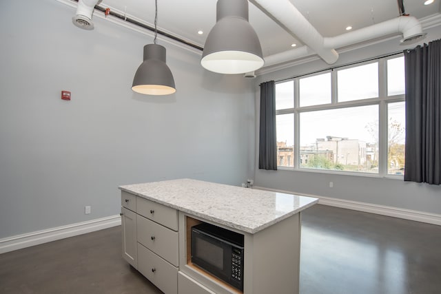 kitchen featuring light stone countertops, ornamental molding, decorative light fixtures, white cabinets, and a kitchen island