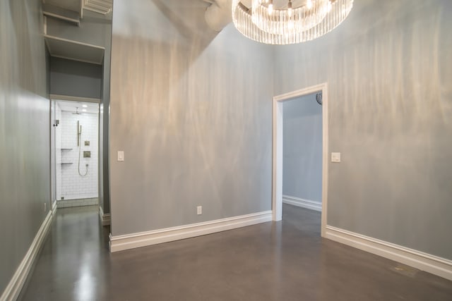 spare room featuring a towering ceiling and an inviting chandelier