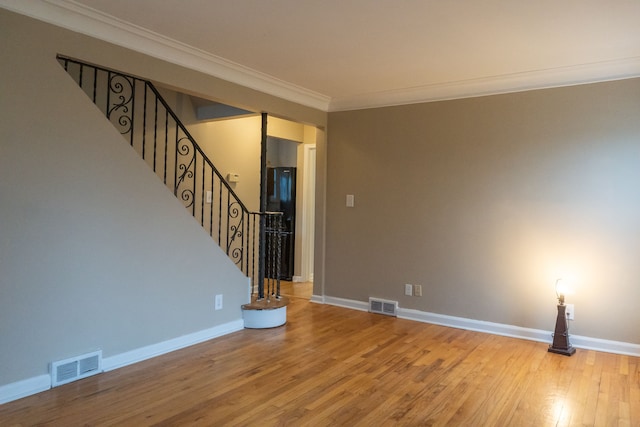 unfurnished living room featuring hardwood / wood-style flooring and crown molding