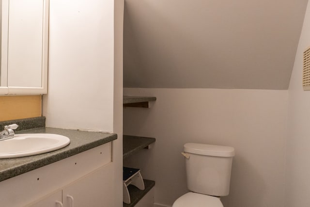 bathroom featuring vanity, vaulted ceiling, and toilet