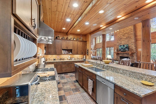 kitchen featuring light stone counters, stainless steel dishwasher, sink, wooden ceiling, and a stone fireplace