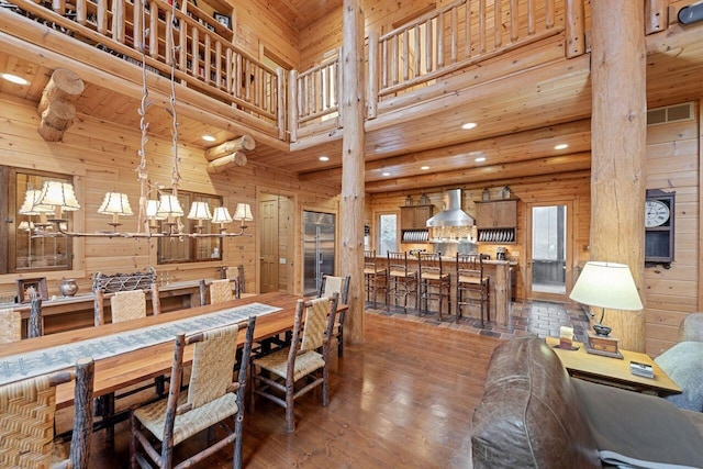 dining area with dark hardwood / wood-style flooring, a high ceiling, and wooden walls