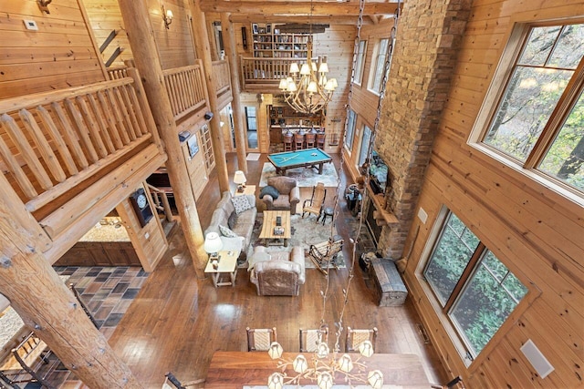 living room featuring wood walls, hardwood / wood-style floors, a high ceiling, and an inviting chandelier