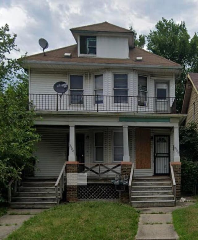 view of front facade featuring a balcony, covered porch, and a front yard