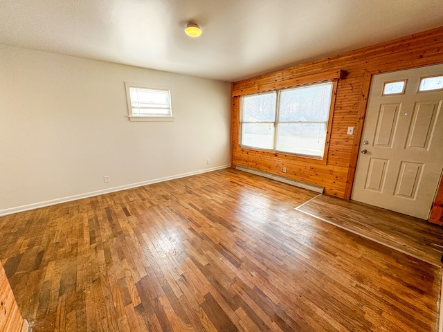 entryway featuring hardwood / wood-style flooring, baseboard heating, and wood walls