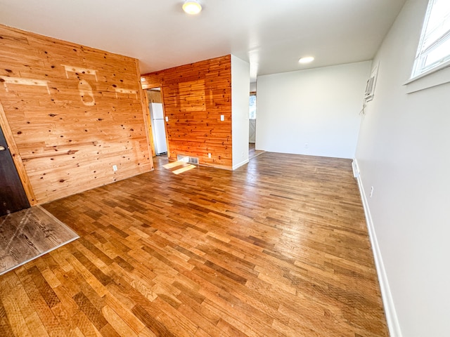 unfurnished room with hardwood / wood-style floors and wooden walls