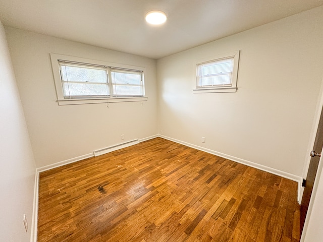 empty room featuring hardwood / wood-style floors and a baseboard heating unit