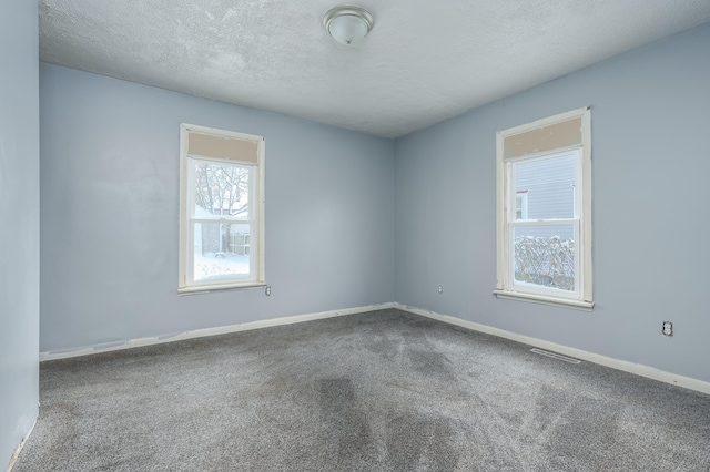 carpeted spare room with a textured ceiling