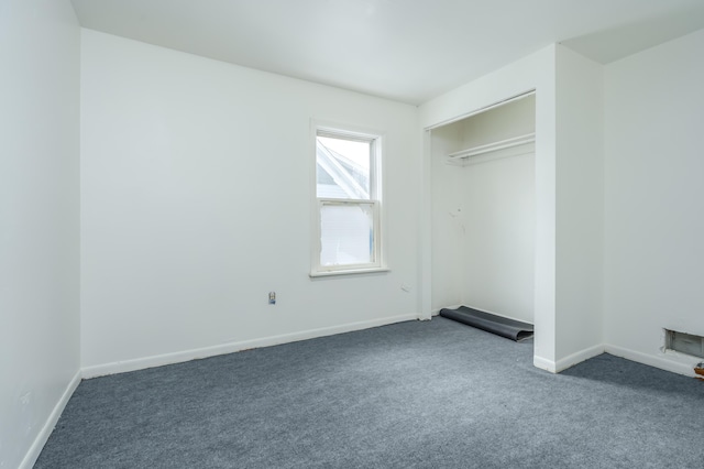 unfurnished bedroom featuring dark carpet and a closet