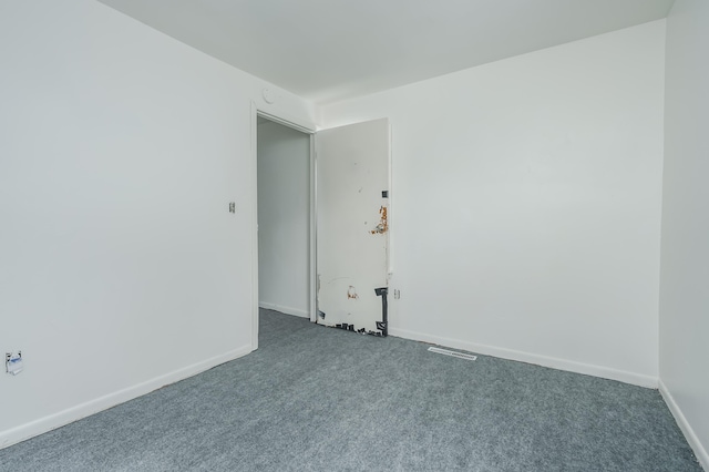 unfurnished room featuring dark colored carpet