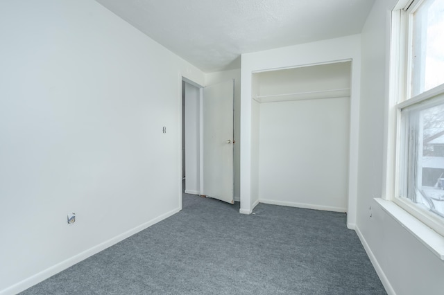 unfurnished bedroom featuring multiple windows, a closet, and dark colored carpet