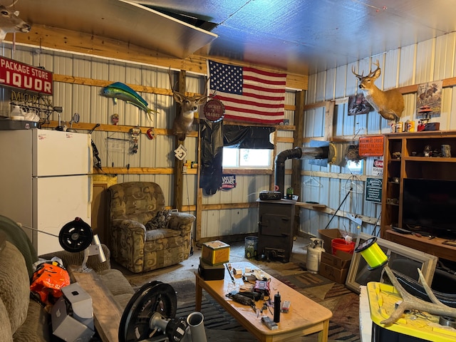 interior space featuring a workshop area, white fridge, a wood stove, and wooden walls