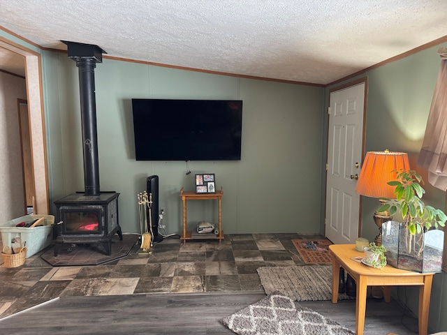 living room with a textured ceiling, dark hardwood / wood-style flooring, a wood stove, and ornamental molding