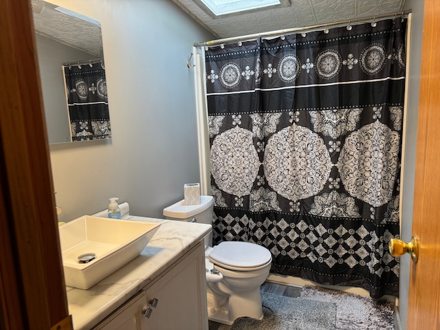 bathroom with a shower with shower curtain, vanity, a skylight, and toilet