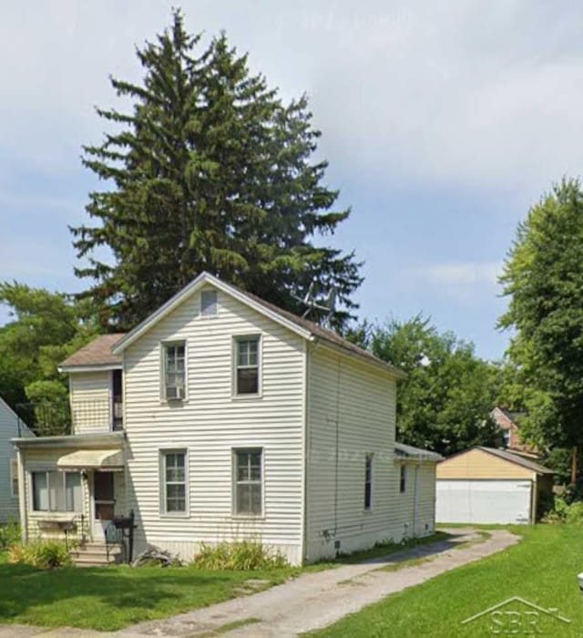 view of front of home with a front yard, an outbuilding, and a garage